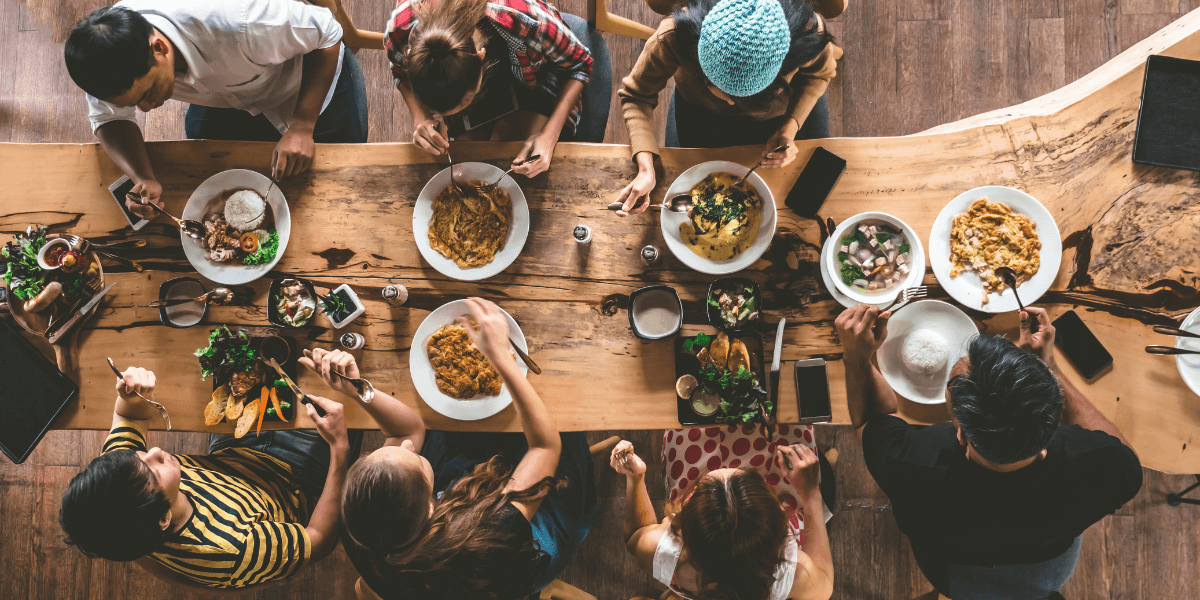 An image of people gathered around a table to have dinner